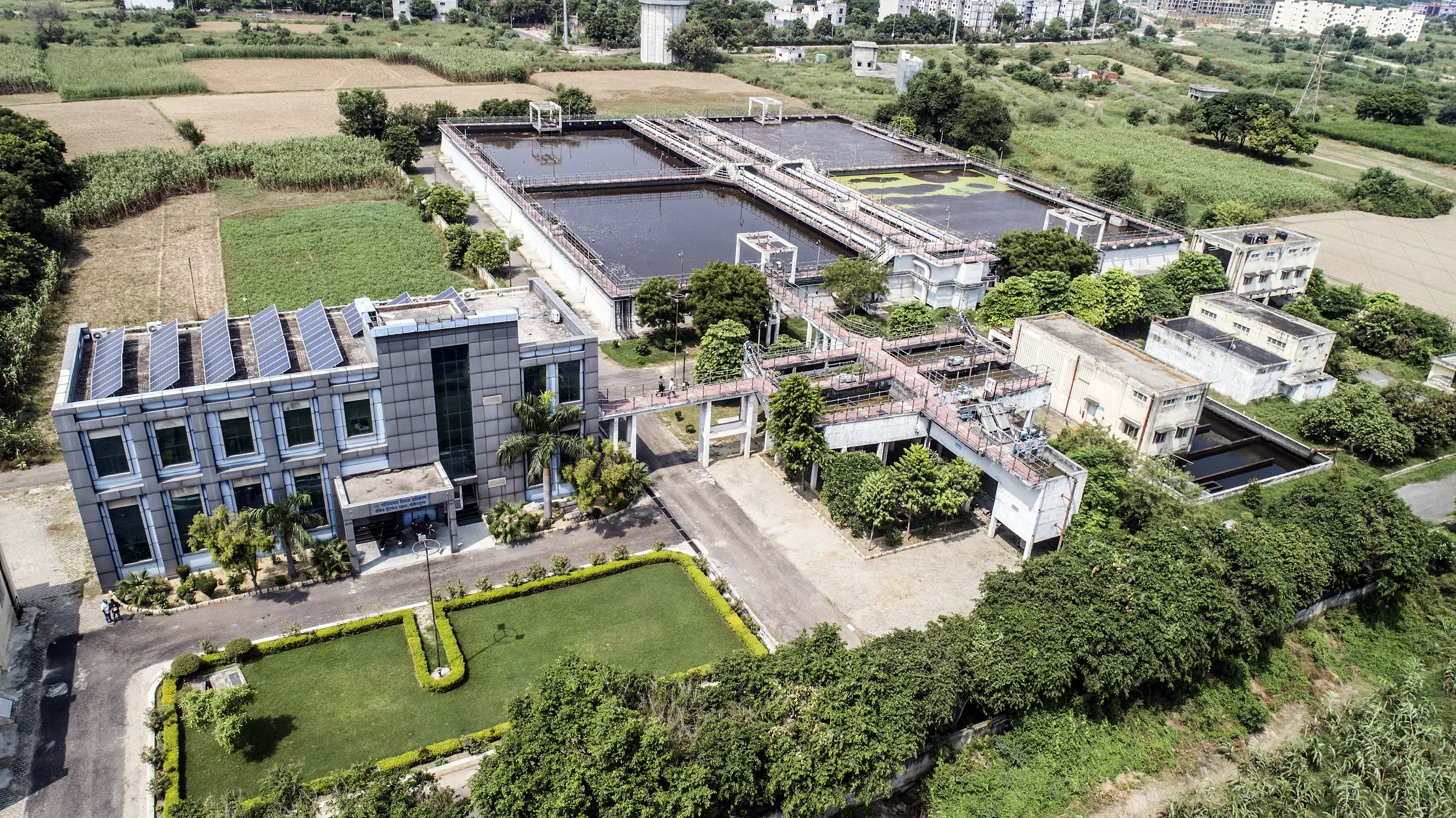 Aerial view of an industrial facility complex with an office building and open-air process tanks.